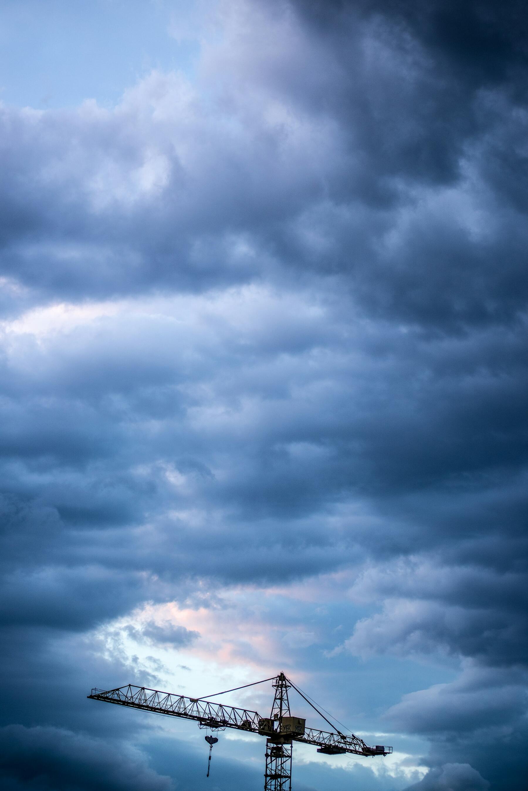 A tower crane under a heavy bank of storm cloud.